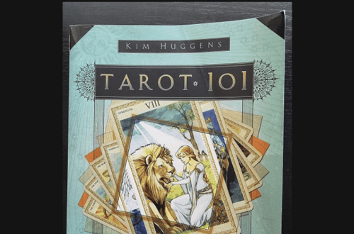 Book cover of Tarot 101 by Kim Huggens featuring an illustration of a woman taming a lion, surrounded by tarot cards. The text above reads Tarot 101 Book Review on a white background.