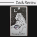 A tarot card illustration of a white tiger sits beneath a crescent moon, holding a sphere with a galaxy pattern. The card is labeled The High Priestess from The Wild Unknown Tarot. Deck Review is written above the card.