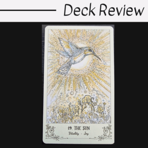 A tarot card from the Spiritsong Tarot titled 19. THE SUN features a vibrant hummingbird flying near a radiant sun, with golden rays and blooming flowers below. The words Vitality and Joy are written at the bottom.