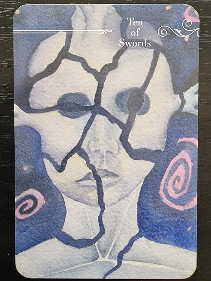 A Guardian Tarot card labeled Ten of Swords shows a face fragmented by dark cracks, with empty eyes and swirling pink shapes on a blue background, creating a haunting and surreal effect.
