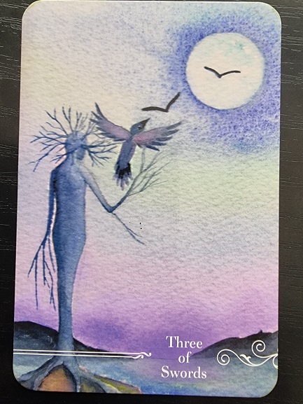 The Guardian Tarot's Three of Swords shows a slender, tree-like figure holding a branch. Two birds fly near a large moon in a purple and blue sky, with hills silhouetted at the bottom.