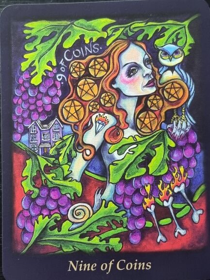 A Bonefire Tarot card titled Nine of Coins shows a woman with red hair, surrounded by grapes and leaves, holding nine gold coins. An owl perches on her shoulder, and a large house appears in the background.