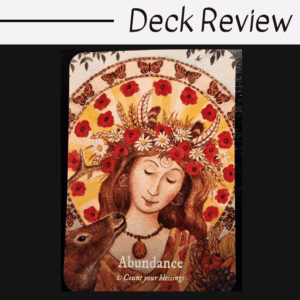 An illustrated card from the Goddess Dream Oracle shows a serene woman with a floral crown, surrounded by flowers and butterflies. A deer nuzzles her. The card reads: Abundance. 1. Count your blessings.