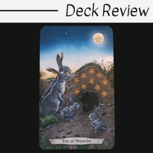 A tarot card from the Animal Totem Tarot, labeled Ten of Pentacles, features three rabbits in front of a burrow at dusk. Ten pentacles are embedded above the entrance, with a full moon overhead. “Deck Review” is written at the top.