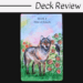 A tarot card with an illustration of a wolf standing in grass and flowers. The card reads “WOLF Nine of Fossils” with a small bird nearby. The image background is pastel, and “Deck Review” is written above.