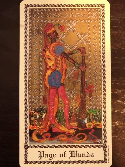 A tarot card from The Medieval Scapini Tarot, the Page of Wands depicts a young person in colorful medieval attire holding a tall, leafy wand. Ornate golden patterns grace the background, with green plants at their feet.