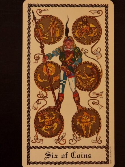 A tarot card from The Medieval Scapini Tarot titled Six of Coins shows a standing figure in colorful clothes holding a long staff, surrounded by six ornate gold coins, each containing a different detailed scene or symbol.