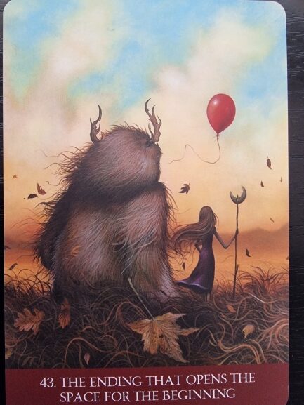A furry creature with horns sits beside a girl in a purple dress holding a staff, as she releases a red balloon. Autumn leaves float around them under a soft, cloudy sky. Text reads: Into the Lonely Woods—the ending that opens the space for the beginning.