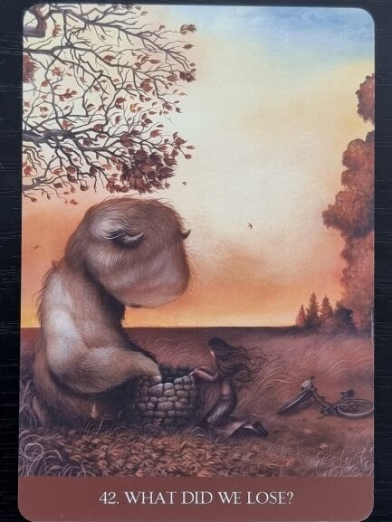 A furry, bear-like creature gently holds a human skull with a red flower growing from it. Kneeling on the grass, it gazes at the skull. Below, text reads: 34. Our Shadows Are Beautiful—an image inspired by Into the Lonely Woods.