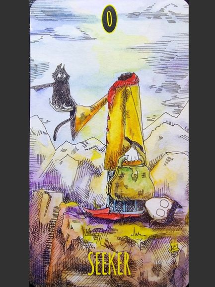 A whimsical headless figure in a yellow cloak stands on a cliff with a satchel, red shoes, and a white mask by their feet—a scene from The Shadowland Tarot. A black cat sits on their outstretched arm. Mountains and a bright sky are in the background.
