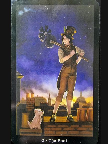 A person in vintage attire stands confidently on a rooftop at dusk, holding a chimney sweep brush. A small white dog looks up at them. The Steampunk Tarot inspires the city skyline and starry sky behind this card labeled 0 The Fool.