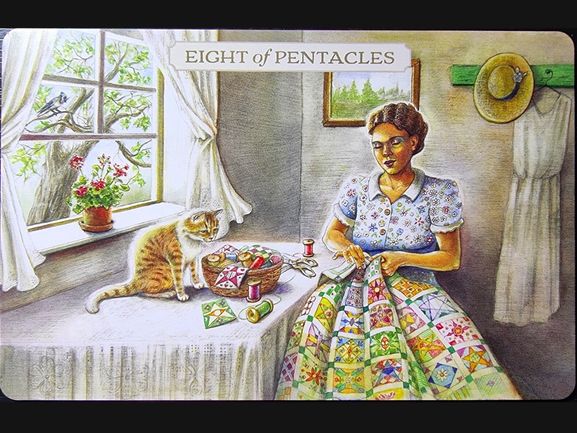 A woman sits by a window quilting a colorful patchwork; a cat watches her on the table. Sunlight streams in, with flowers in a vase and a hat on the wall, evoking the tranquil charm of Pastoral Tarot. The card reads Eight of Pentacles.