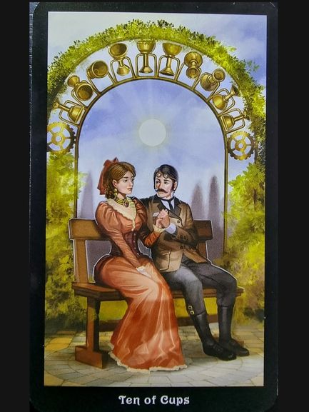 A tarot card titled Ten of Cups from The Steampunk Tarot shows a Victorian-era couple sitting on a bench under an arch decorated with ten golden cups. The content couple holds hands, surrounded by greenery and a bright sky in the background.