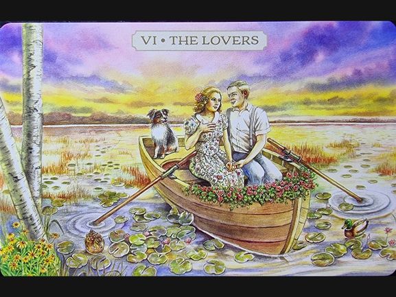 A couple sits closely together in a flower-filled rowboat on a lily-covered lake at sunset, holding hands. A dog sits beside them, and a duck floats nearby. The card reads VI THE LOVERS from the Pastoral Tarot deck.