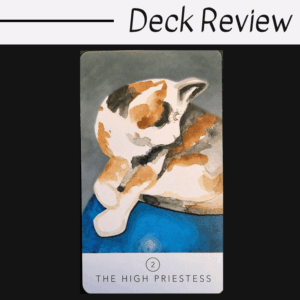 A tarot card labeled The High Priestess from the White Sage Tarot features an illustration of a calico cat, lounging with its head turned to the side, on a soft blue surface. The text Deck Review appears above the card.