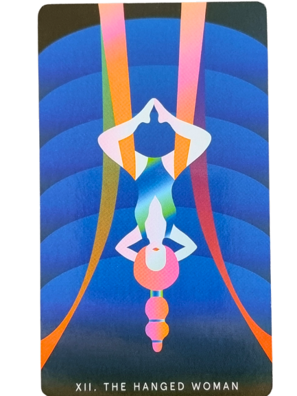 A stylized Mystic Mondays Tarot card shows a woman hanging upside down in a meditative pose, surrounded by vibrant, curved, rainbow-colored lines on a blue background. The text at the bottom reads XII. THE HANGED WOMAN.