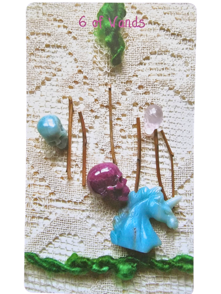 A Crystal Skull Tarot card titled The Sun features a large amber-like sphere in the center, encircled by a red textured spiral, with a smaller amber-like stone below, set on a white patterned surface. The Roman numeral XIX tops the card.