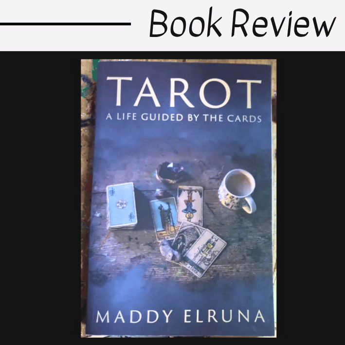 A copy of Tarot: A Life Guided by the Cards by Maddy Elruna rests on a surface, its cover adorned with tarot cards, a key, and a cup of tea. "Book Review" is prominently displayed above the captivating scene.