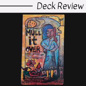 A colorful tarot card illustration with the words MULL IT OVER beside a figure in a blue robe. A reclining figure with a red hat, flowers, and a cat rest below. The top text reads Deck Review: Manifesting Your Greatness.