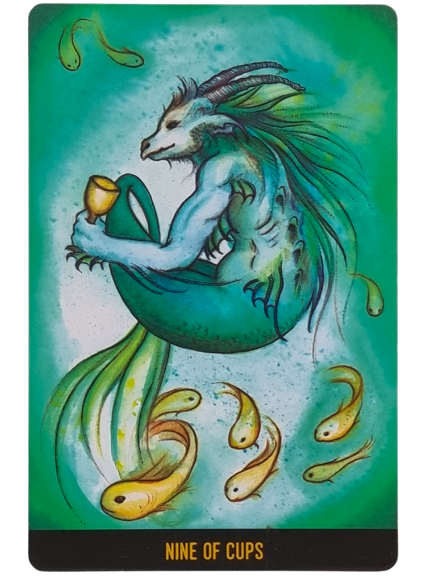 A tarot card from The Penumbra Tarot titled Nine of Cups shows a blue goat-fish creature holding a cup, surrounded by nine golden fish, all set against a swirling green and blue aquatic background.