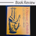 A book titled A Dictionary of Symbols by Juan Eduardo Cirlot with a yellow cover featuring an illustrated hand and small figures. Above the book is text that reads Book Review, highlighting A Dictionary of Symbols as the focus.