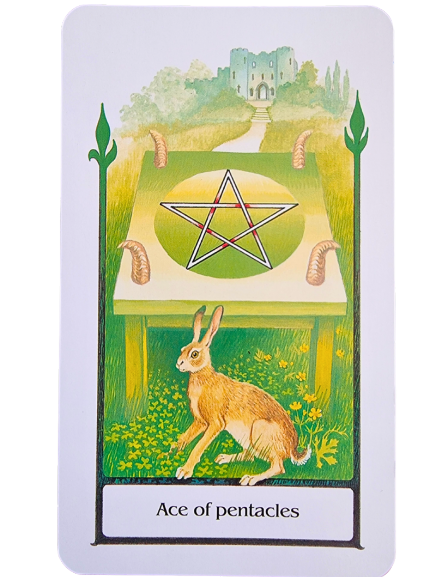 A Tarot of the Old Path card depicting the Ace of Pentacles, featuring a hare in a grassy field, a large pentacle on a green altar, and a castle in the background beneath a bright sky.