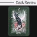 A tarot card from The Witch's Familiar Runic Oracle features a black cat perched on a deer skull, surrounded by pink flowers, rays of light, a crescent moon, and rune above. Eihwaz is at the bottom. Top text: Deck Review.