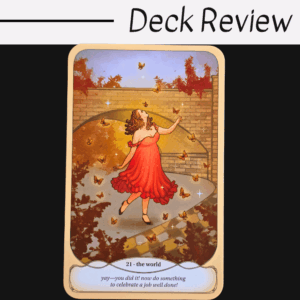 A Cozy Witch Tarot card titled 21 - the world shows a woman in a red dress dancing joyfully among swirling butterflies, with a stone wall and autumn trees behind her. The caption says, yay—you did it! Now do something to celebrate a job well done!.