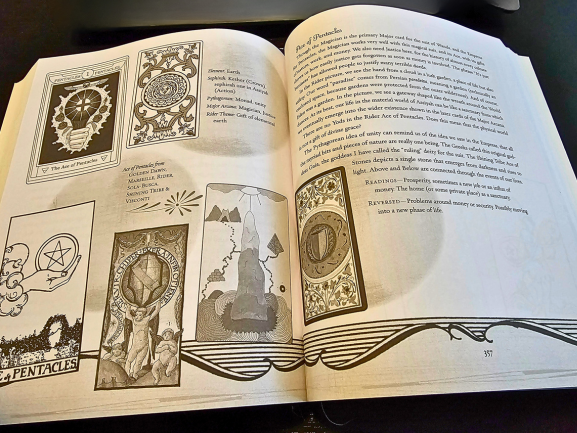 An open book displaying Tarot Wisdom with illustrated tarot cards on the left page and text bordered by symbols on the right. The pages feature intricate black-and-white designs and a mystical theme.