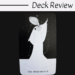 A black and white tarot card from the Black Violet tarot titled The Hierophant shows a robed figure with an elaborate headdress pointing upward, surrounded by dots and stars. Above, text reads Deck Review on a white background.