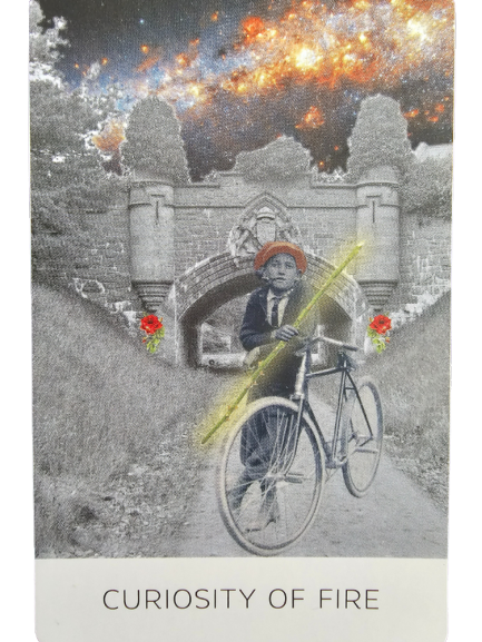 A black-and-white photo shows a young boy on a bicycle holding a glowing yellow stick. He wears a red hat. Behind him, a stone bridge with floral accents evokes The Rosebud Tarot, while a fiery galaxy fills the sky. Text reads “CURIOSITY OF FIRE.”.