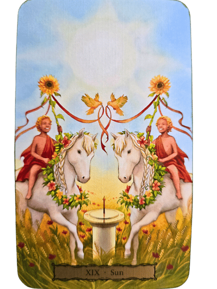 Two smiling children in red cloth ride white horses adorned with flowers. Above them, two sunflowers, birds, and red ribbons form a heart. Sunlight fills the sky. Below, a candle on a pedestal labeled XIX - Sun hints at Tarot of the Witch's Garden magic.