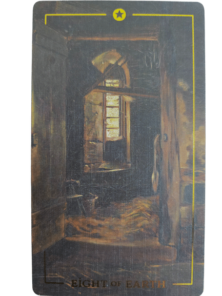 A tarot card from the Folkloric Forest Tarot labeled Eight of Earth shows a dimly lit, rustic room with a window letting in light. The scene is framed by a yellow border with a yellow star at the top.