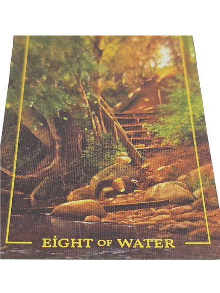 A tarot card from the Folkloric Forest Tarot, the Eight of Water, shows a rocky stream with large stones and a staircase leading up through a sunlit, leafy forest. The scene feels peaceful and inviting.