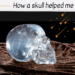 A clear crystal skull sits on a textured brown surface under the title How a skull helped me, with yellow star-like sparkles decorating the top right corner—perfect for fans of unique crystal skulls.