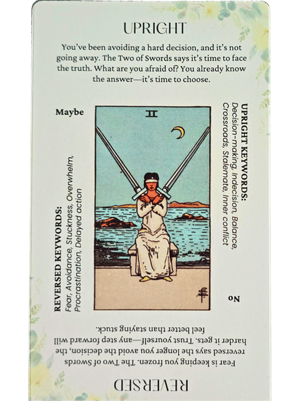 A tarot card, the Two of Swords, shows a blindfolded woman holding two crossed swords by water under a crescent moon. Upright and reversed meanings and keywords are printed around the card, similar in detail to Star and Strength Tarot illustrations.